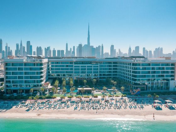 Aerial view of the Mandarin Oriental Jumeira resort in Dubai, with its beach, pools and gardens, and the city skyline with the Burj Khalifa behind