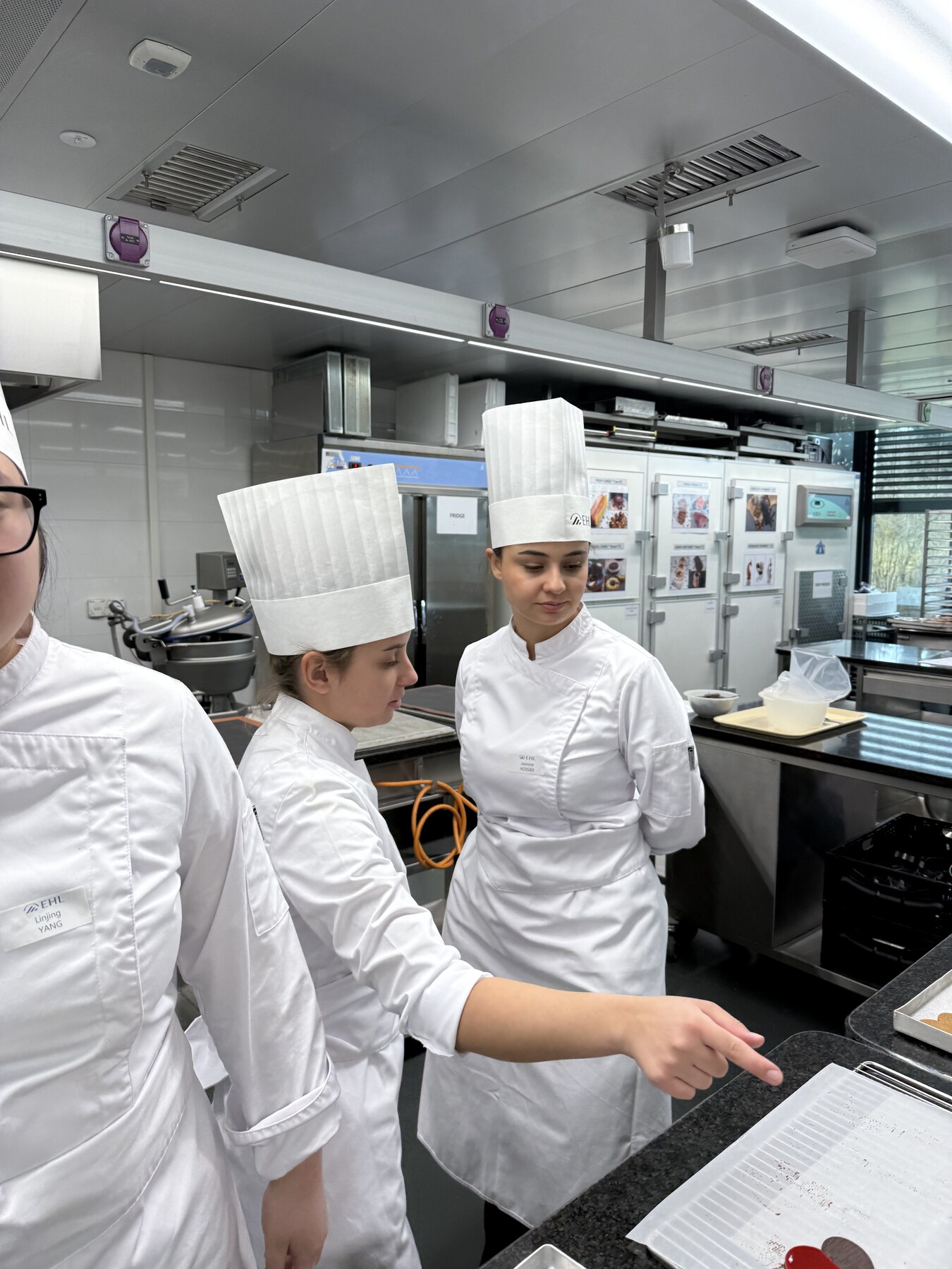 EHL students in chef uniforms working together in the teaching kitchen