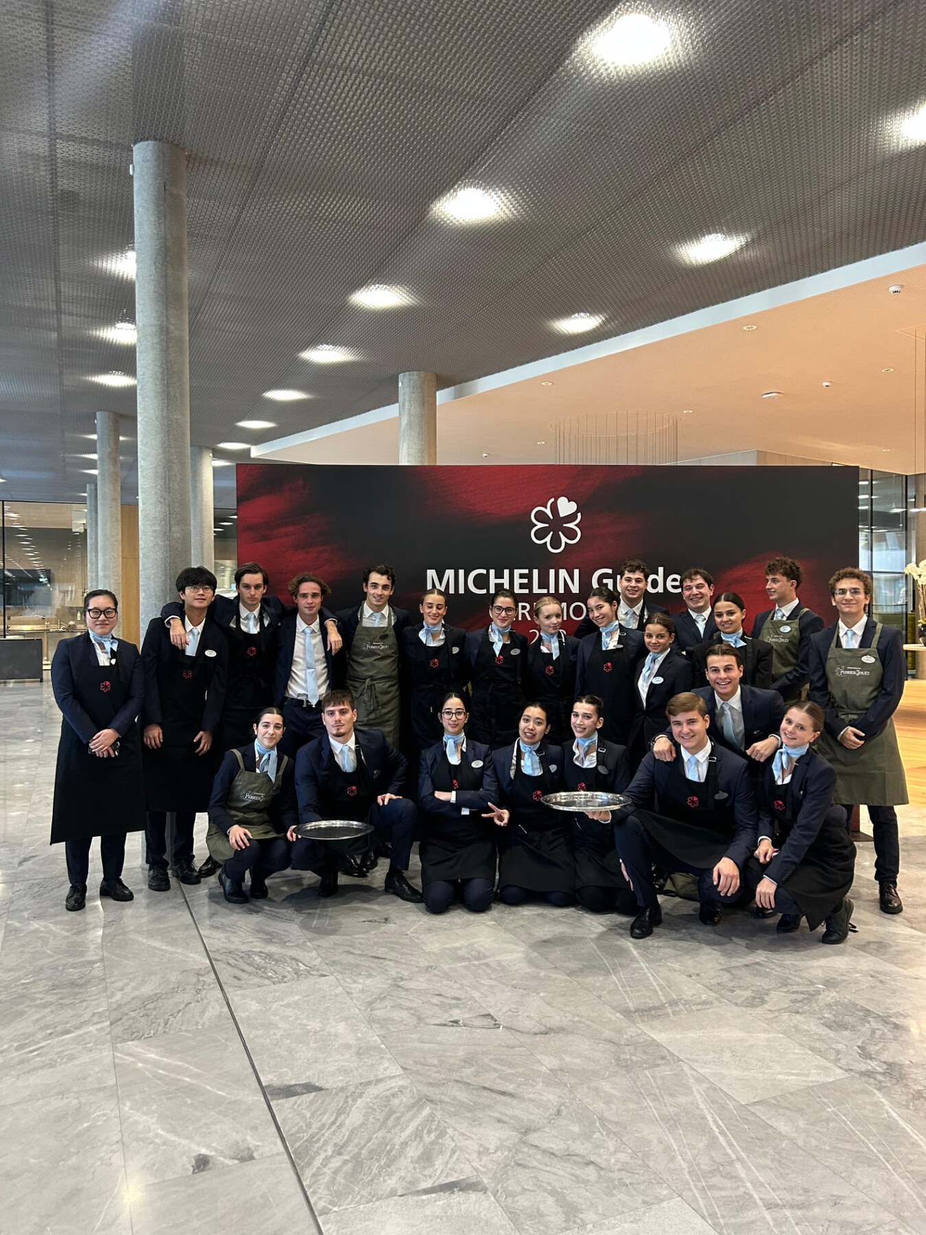 Lillian's EHL service team in uniform in front of the Michelin Guide display